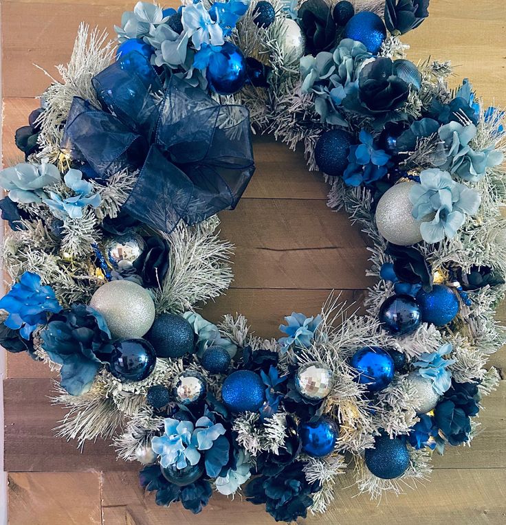 a blue and silver christmas wreath on a wooden floor