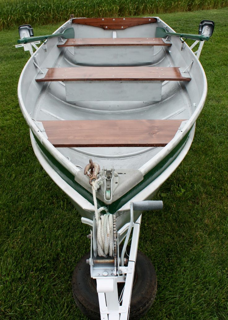 a small boat sitting on top of a lush green field