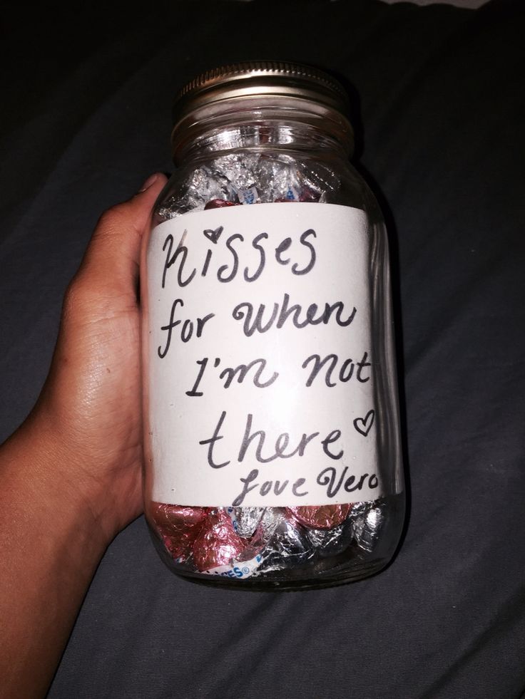 a hand holding a jar filled with lots of candy and some writing on the lid