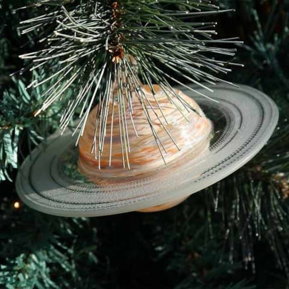 an ornament hanging from a christmas tree in the shape of saturn with pins stuck to it