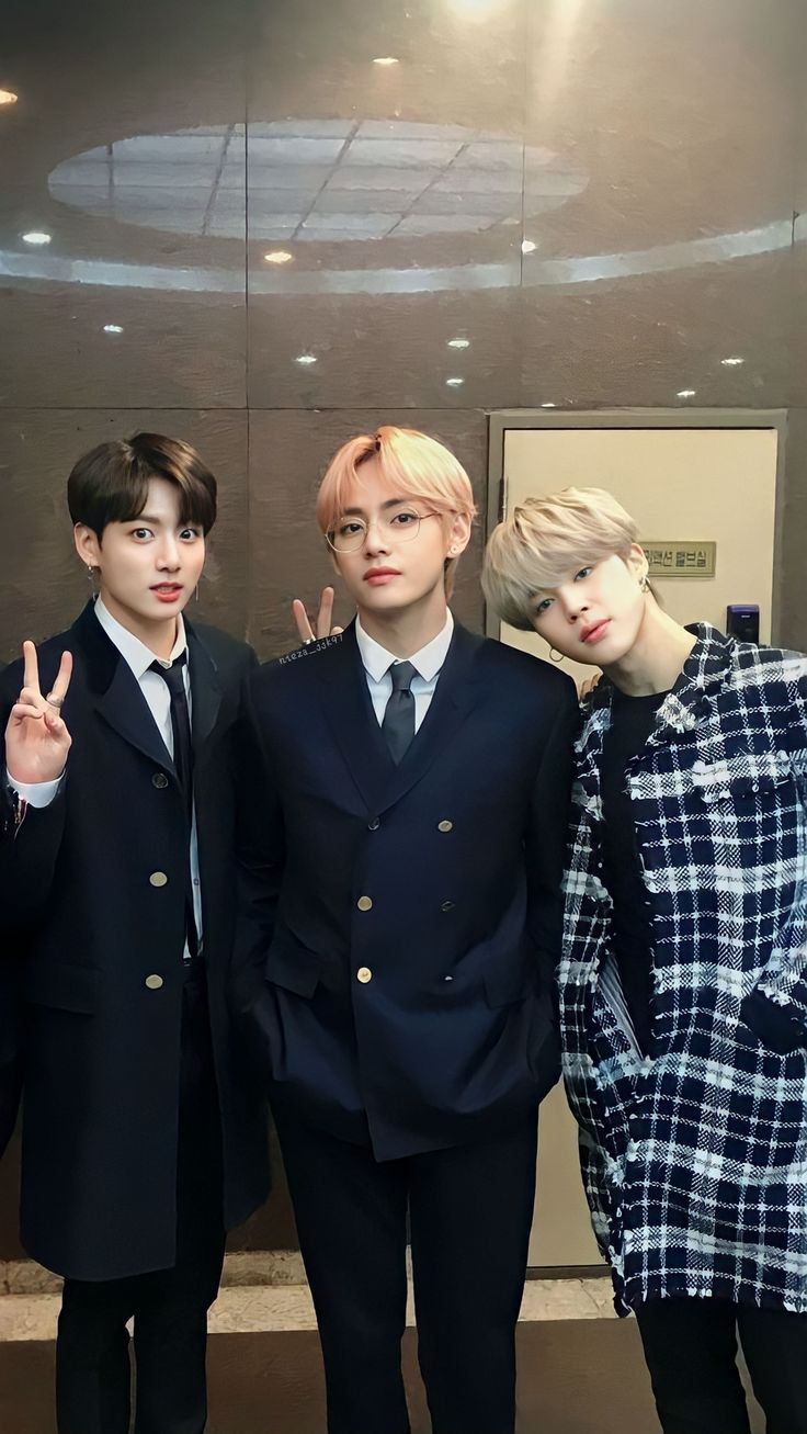 three young men posing for a photo in front of a mirror with their fingers up