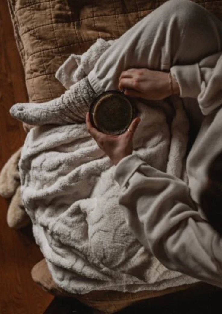 a person laying in bed with an elephant blanket on top of them and holding a bowl