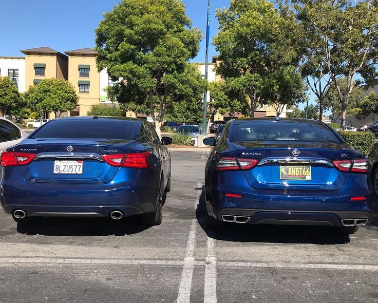 two blue cars parked in a parking lot next to each other on a sunny day