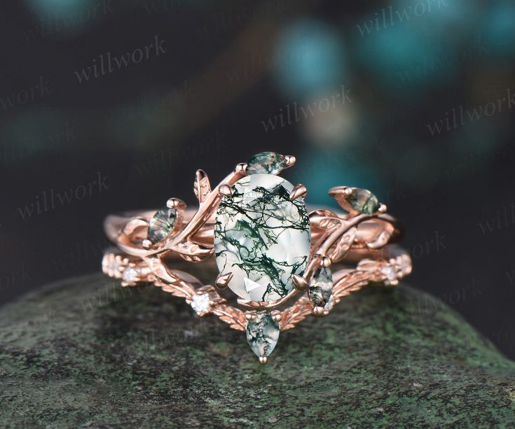 a green and white stone ring sitting on top of a mossy rock with leaves around it