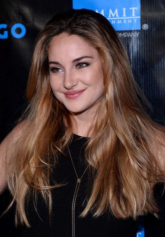 a woman with long blonde hair smiling at the camera and wearing a black top on