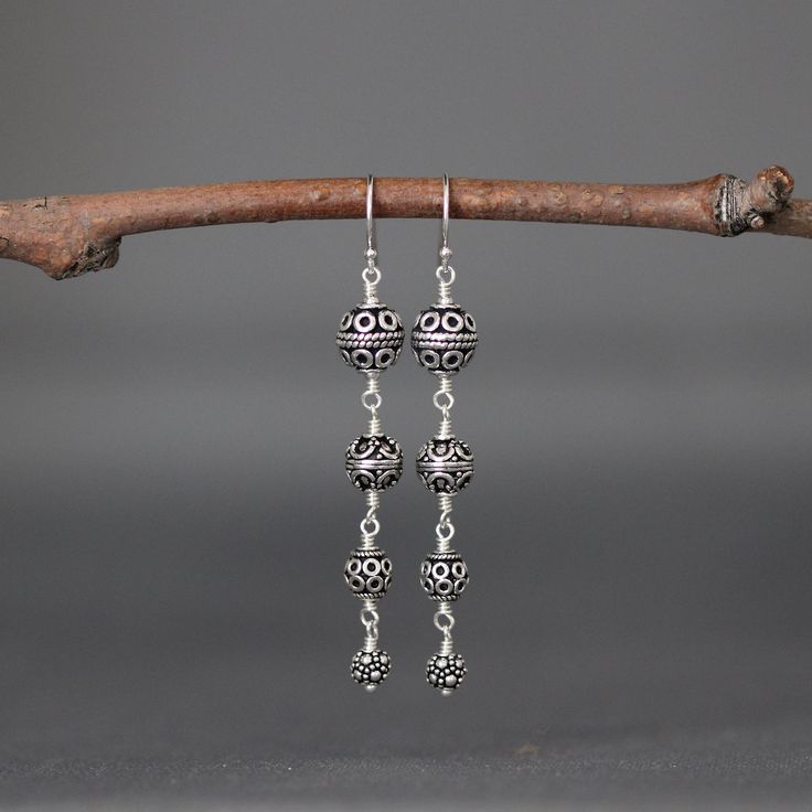 "Four gorgeous and detailed graduated Bali Silver beads are wire wrapped to create these gorgeous statement earrings. These dangle from balled silver earwires. Perfect dramatic earrings for anyone to wear everyday or save for a special occasion. First Bali Silver bead: 8mm Second Bali Silver bead: 7mm Third Bali Silver bead: 6mm Fourth Bali Silver bead: 5mm Total length of earrings: 2 3/8\" All silver is sterling. As the owner, maker, designer, and curator of this shop, I take great pride in pro Sterling Silver Beaded Earrings For Jewelry Making, Elegant Silver Beaded Earrings Wire Wrapped, Elegant Silver Beaded Earrings With Wire Wrapping, Elegant Nickel-free Chandelier Earrings With Round Beads, Dangling Beads Drop Earrings, Ear Wire Drop Earrings For Jewelry Making, Earrings Bali, Dramatic Earrings, Long Silver Earrings