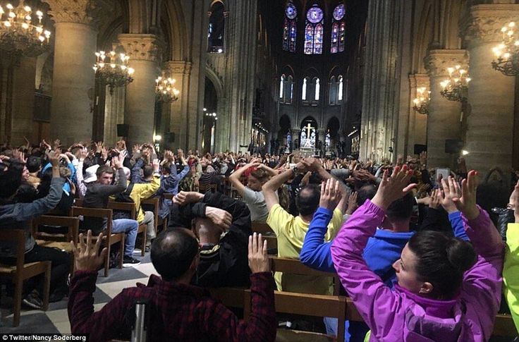 a woman is being held up in the air by people at a church with their hands raised