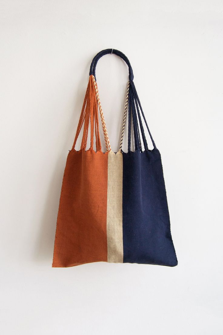 two bags hanging on the wall, one is brown and one is blue with braid handles