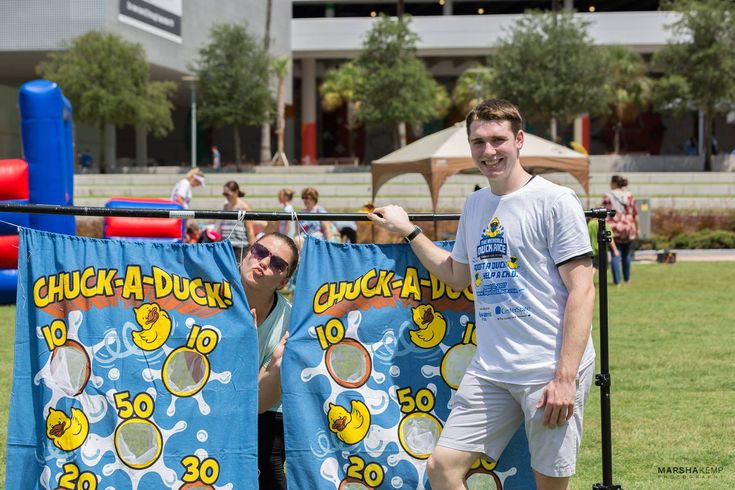 two men standing next to each other in front of a blue and yellow towel with ducks on it