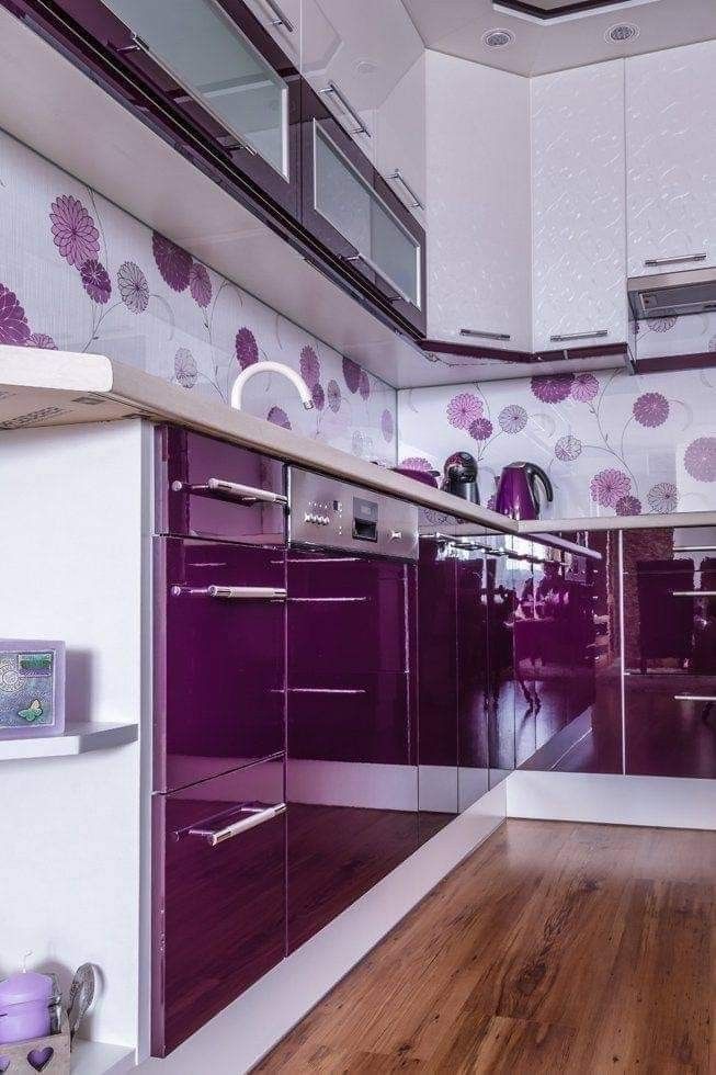 a purple and white kitchen with wooden flooring, cabinets and countertop space in the center