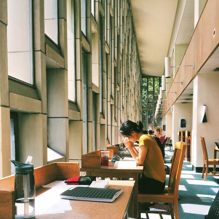 a woman sitting at a table in a restaurant next to a wall with lots of windows