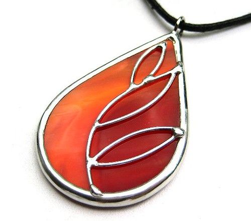 a red and white necklace with an orange tear shaped glass pendant on a black cord