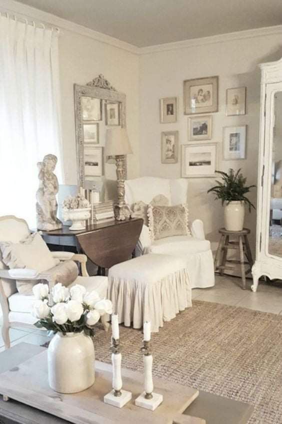 a living room filled with white furniture and flowers on top of a coffee table in front of a mirror