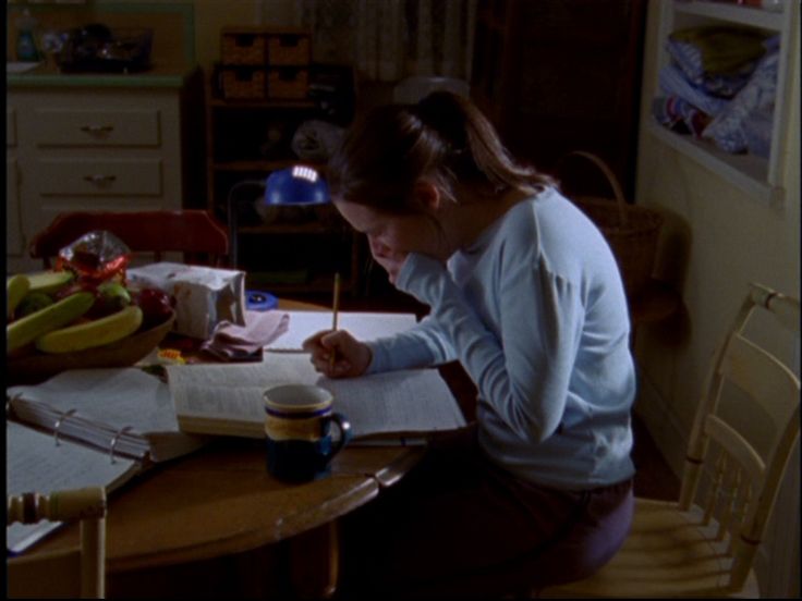 a woman sitting at a table writing on a piece of paper