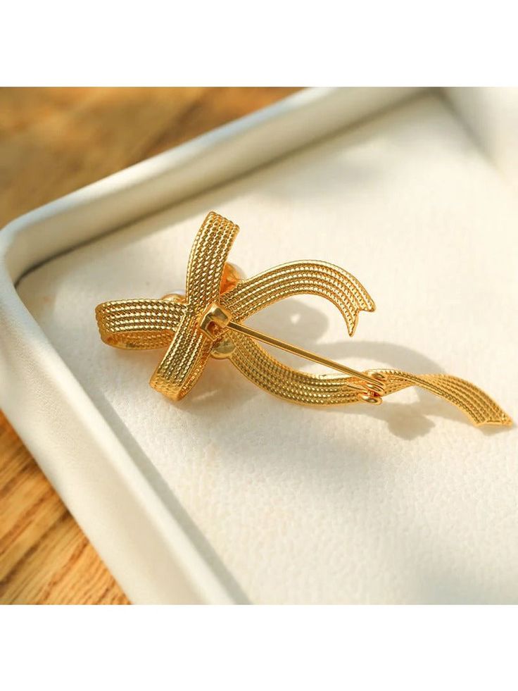 Our Bow Freshwater Pearl Brooch features a charming bow design. Meticulous craftsmanship and the use of high-quality materials create a polished and luxurious accessory that strikes the perfect balance between texture and comfort. Metal: 18K Recycled Gold Plated On Brass Gemstone:Freshwater Pearl Pearl Dimensions:7mm Dimensions:25*60mm Weight:8.5g Elegant Anniversary Brooch With Bow, Elegant Gold Brooches With Ribbon, Elegant Yellow Gold Brooches For Party, Elegant Yellow Gold Party Brooches, Gold Bow Brooches For Formal Occasions, Formal Gold Brooch With Bow, Gift Bow Brooch, Elegant Brooches With Decorative Bow For Anniversary, Elegant Brooches With Ribbon For Gifts