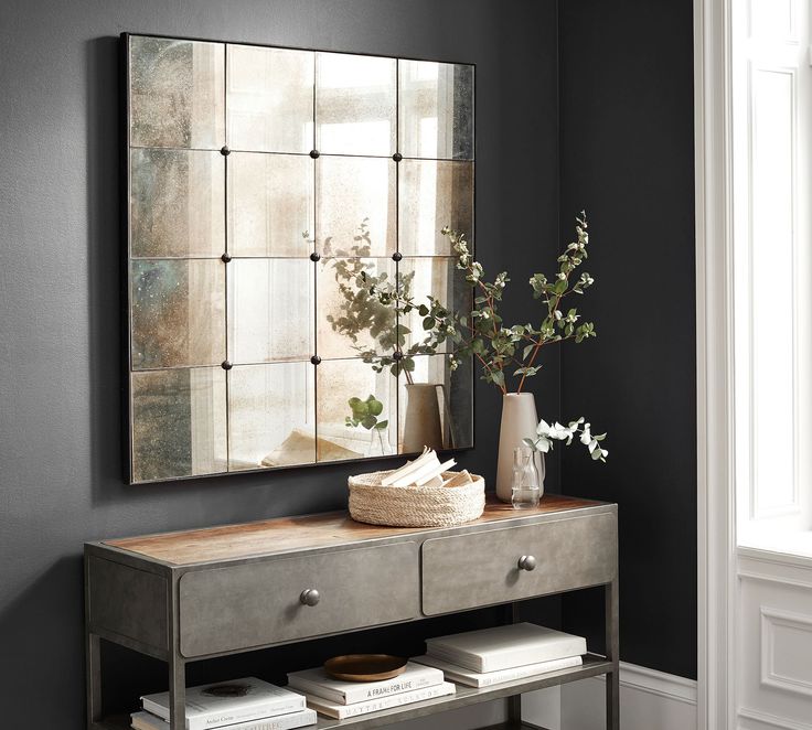 a mirror on the wall above a dresser in a room with black walls and white trim