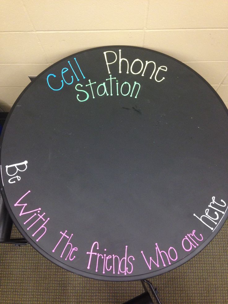 a black table with writing on it that says cell phone station with the friends who ate