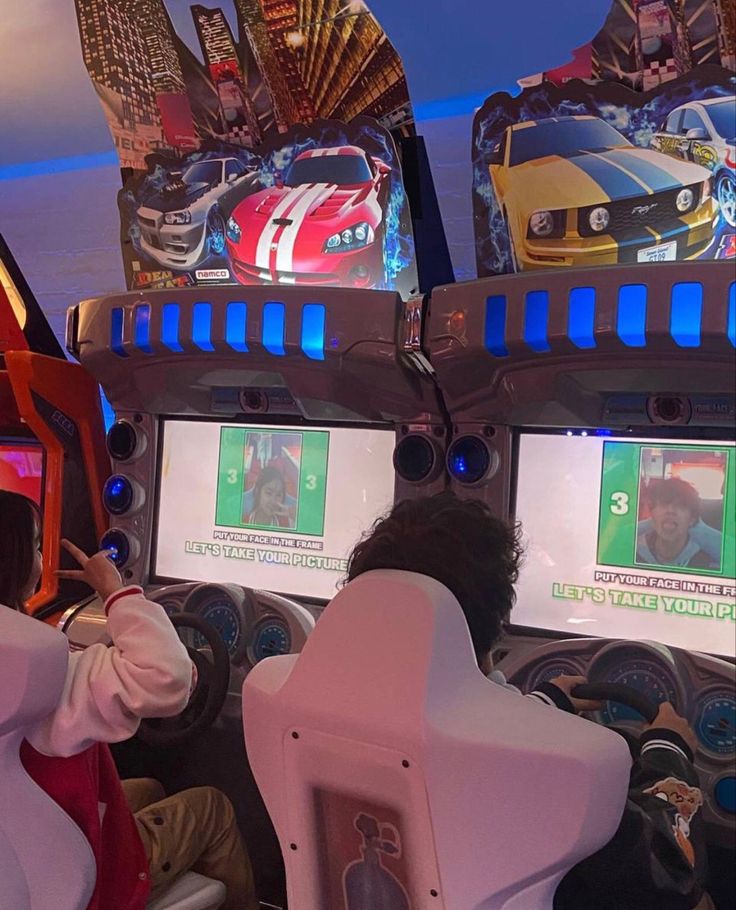 two people are playing video games in a car simulator