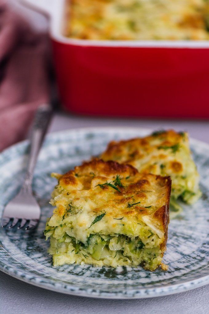 a piece of quiche on a plate with a fork next to the casserole