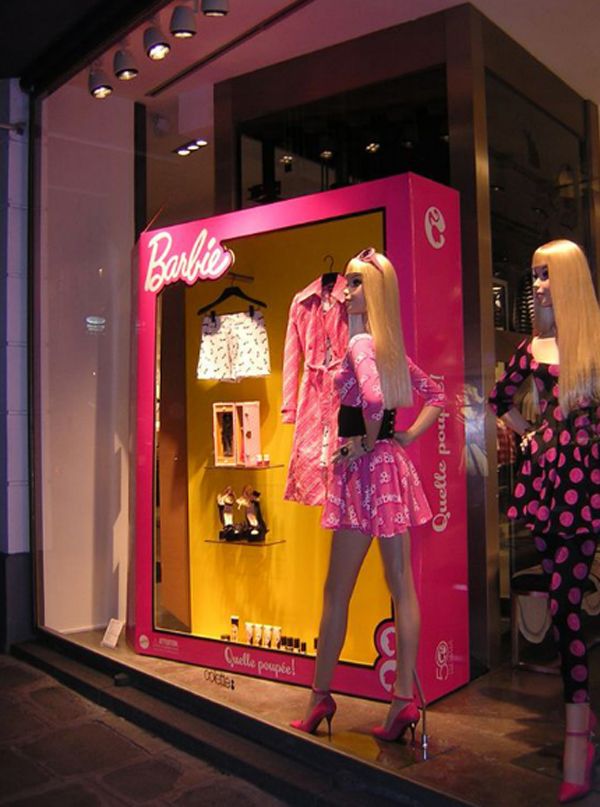 two mannequins dressed in pink and white outfits stand next to a display window