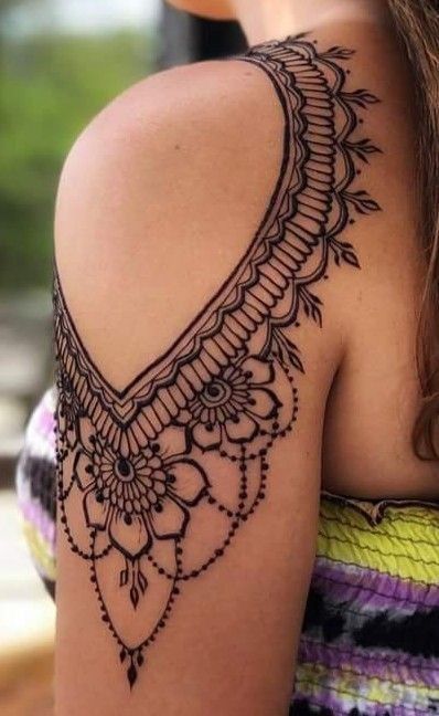 the back of a woman's shoulder with an intricate tattoo design on her arm