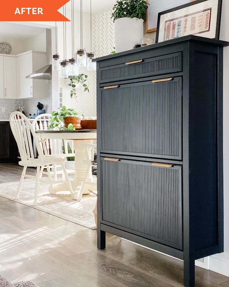 a kitchen with white chairs and a black cabinet next to a dining room table in the background