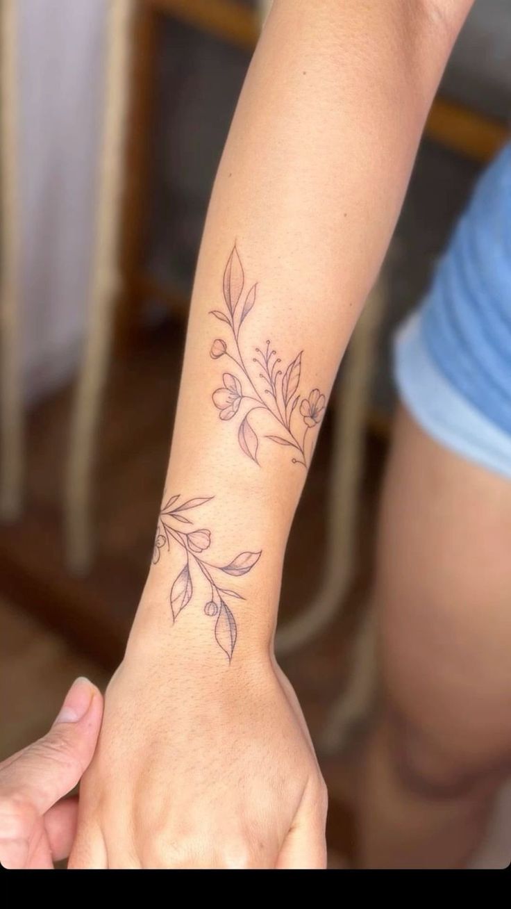 a woman's arm with a flower tattoo on her left wrist and the other hand