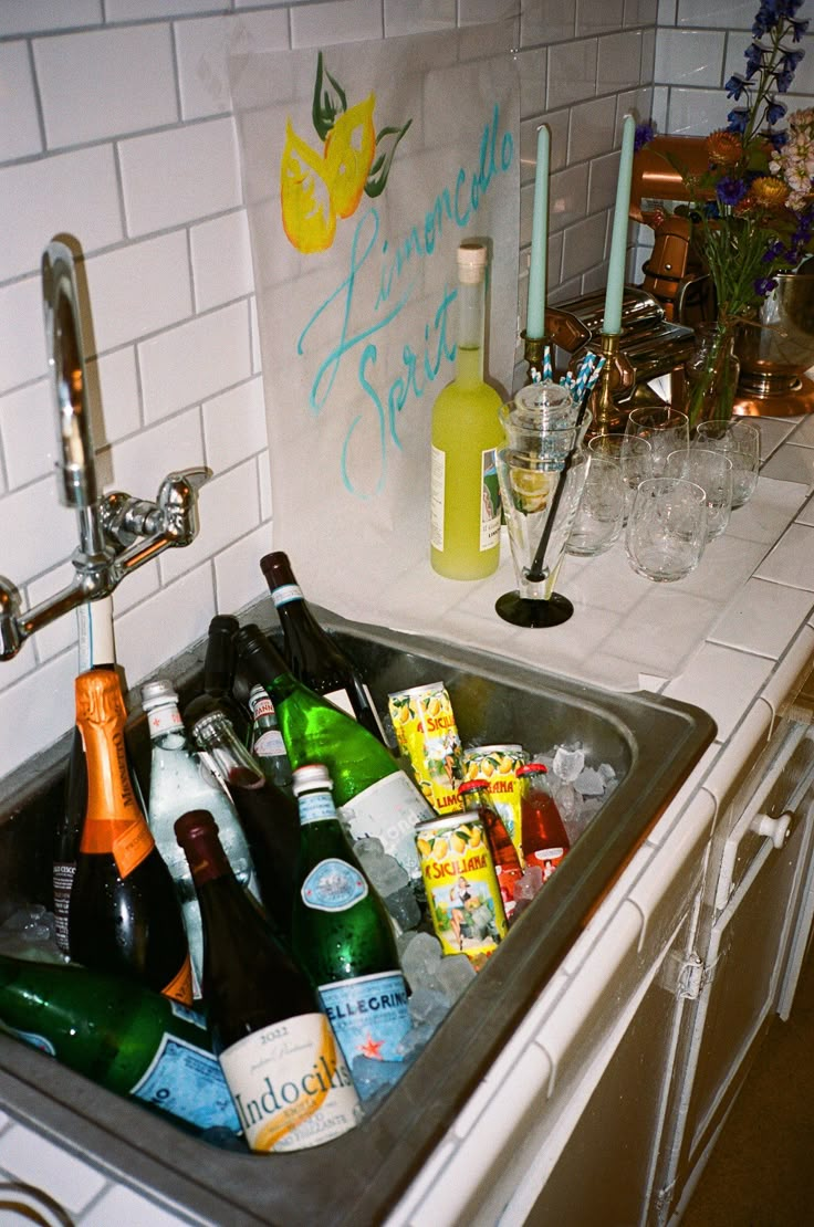 a sink filled with lots of bottles and glasses