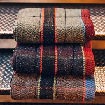 three different colored plaid blankets stacked on top of each other in front of metal grates