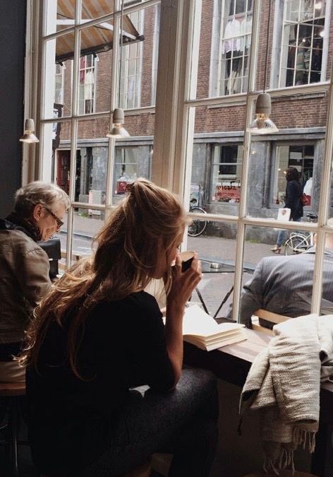 two people sitting at a table in front of a window looking out on the street