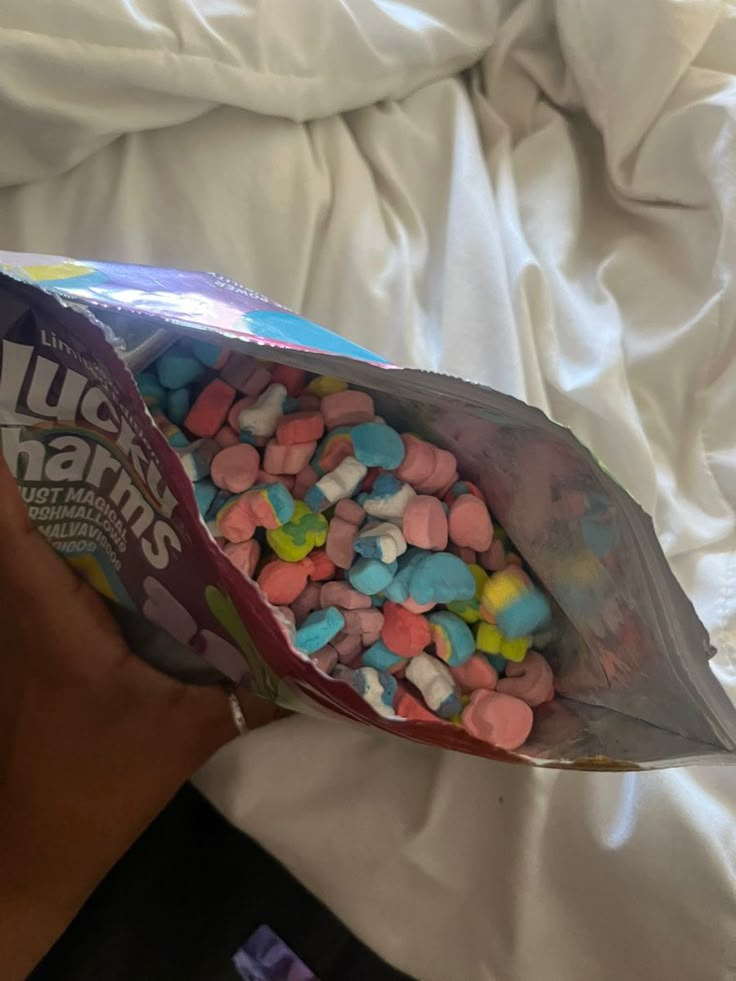 a person holding a bag of marshmallows on top of a bed