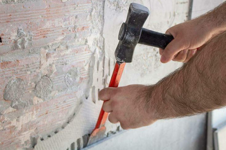 a man with a hammer is working on a brick wall