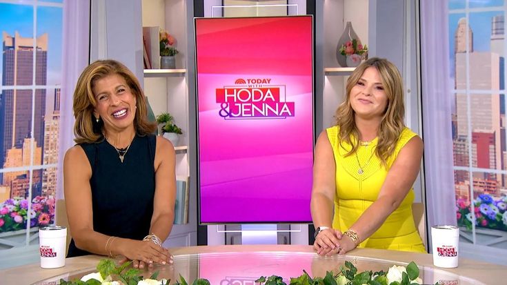 two women sitting at a table with flowers in front of them on the set of hoda and jennyna