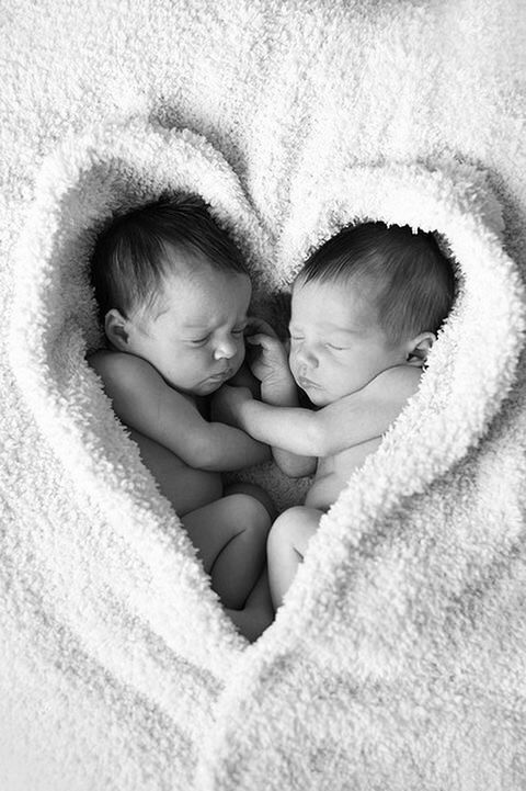 two babies are laying together in a heart shaped blanket with their heads touching each other