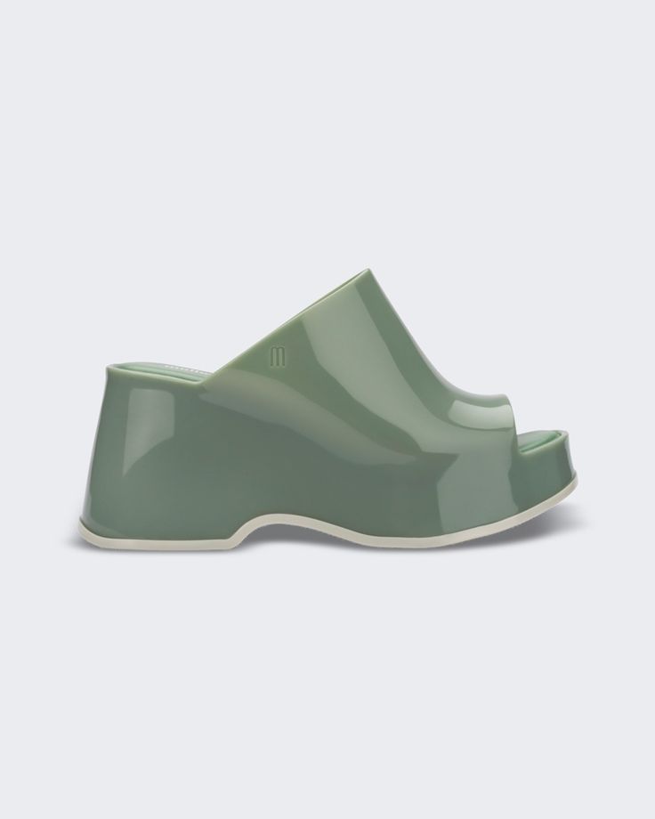 An outer side view of a light green Melissa Patty platform mule Modern Platform Slip-on Slides, Spring Green Sandals With Contrasting Heel Counter, Green Sandals With Contrasting Heel Counter For Spring, Modern Green Heels With Contrasting Heel Counter, Modern Wedge Sandals With Contrasting Heel, Modern Green Heels For Summer, Modern Green Open Toe Mules, Modern Sandals With Deep Heel Cup For Summer, Spring Slides With Rubber Sole And Round Toe