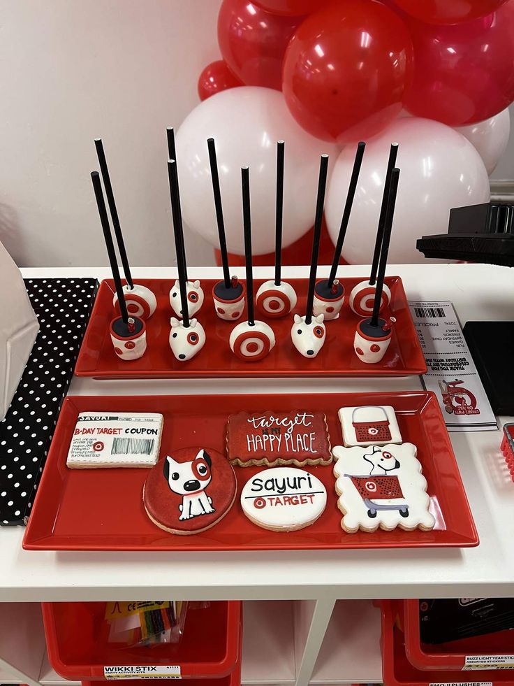 a red tray with black and white decorations on it, along with balloons in the background