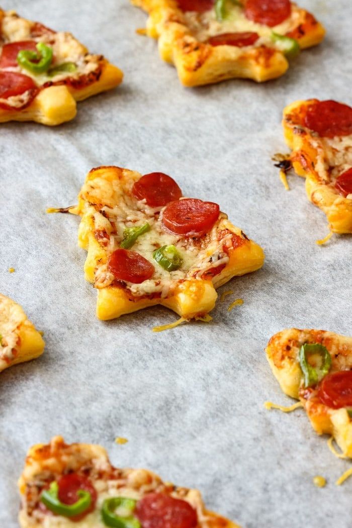 small pieces of pizza sitting on top of a baking sheet covered in cheese and pepperoni