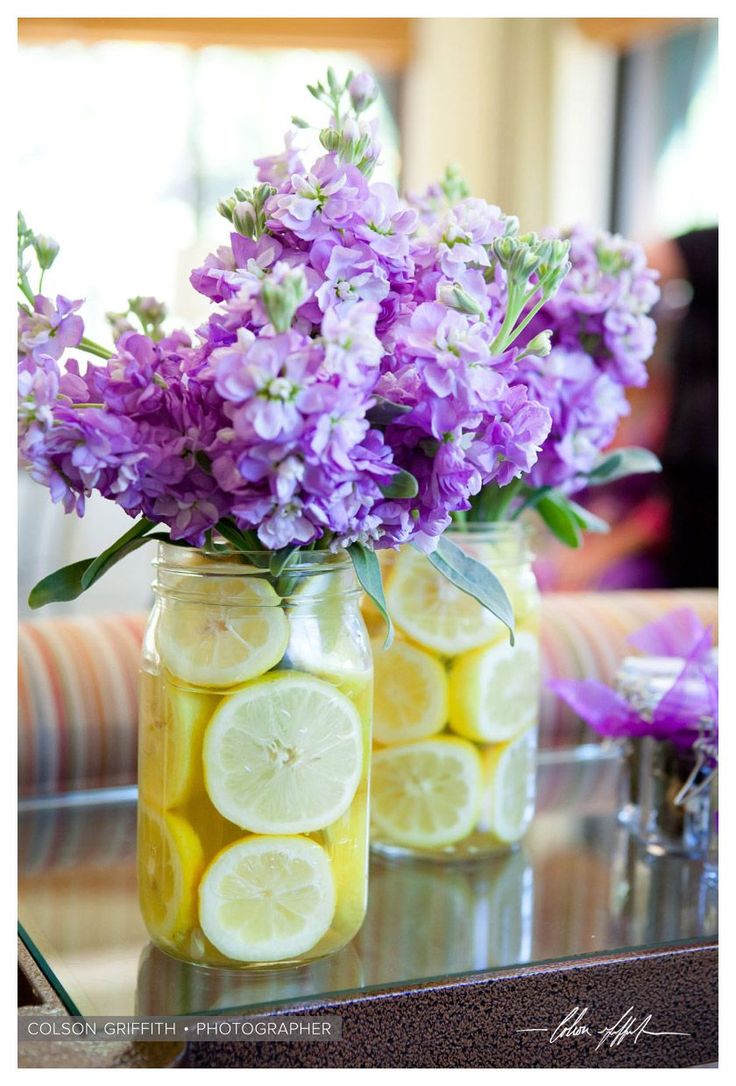 two mason jars filled with lemons and purple flowers