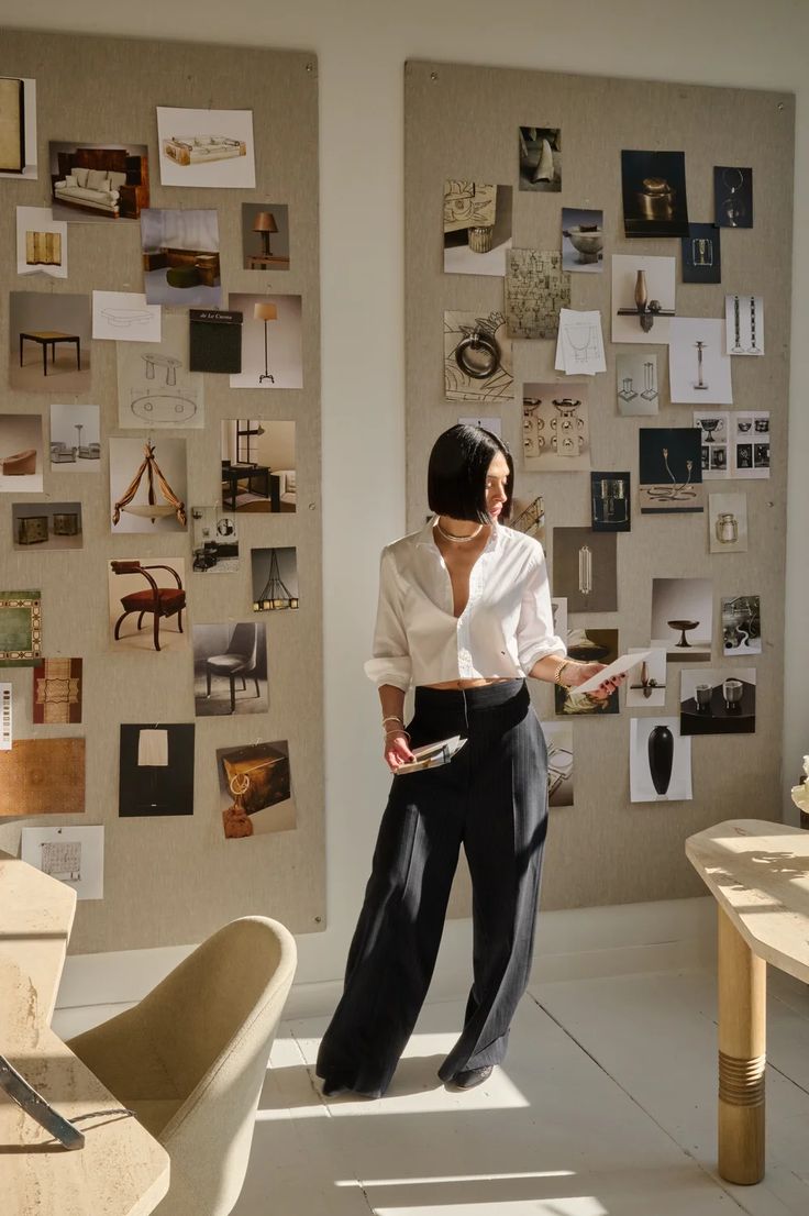 a woman standing in front of a wall with pictures on it