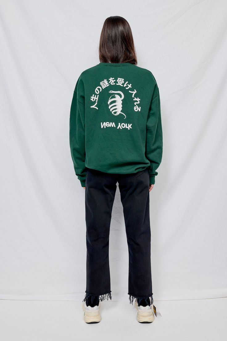 Forest Green Embrace Mystery Sweatshirt from Assembly New York. Text translates to "Embrace The Mystery of Life". Ribbed collar, cuffs and hem. Relaxed fit. - 9.5oz 50/50 blend - Machine Wash Cold - Carmen is 5'10 and wears a size 2, shown in size large - Naoki is 6'2 with a 29" waist, shown in size extra large Sporty Sweatshirt With Back Print, Sporty Sweatshirt With Back Print In Relaxed Fit, Sporty Sweatshirt With Relaxed Fit And Back Print, Heavyweight Long Sleeve Tops For Streetwear, Urban Crew Neck Sweatshirt With Back Print, Urban Sweatshirt With Back Print And Crew Neck, Sporty Long Sleeve Sweatshirt With Back Print, Spirit Gear, 50 50