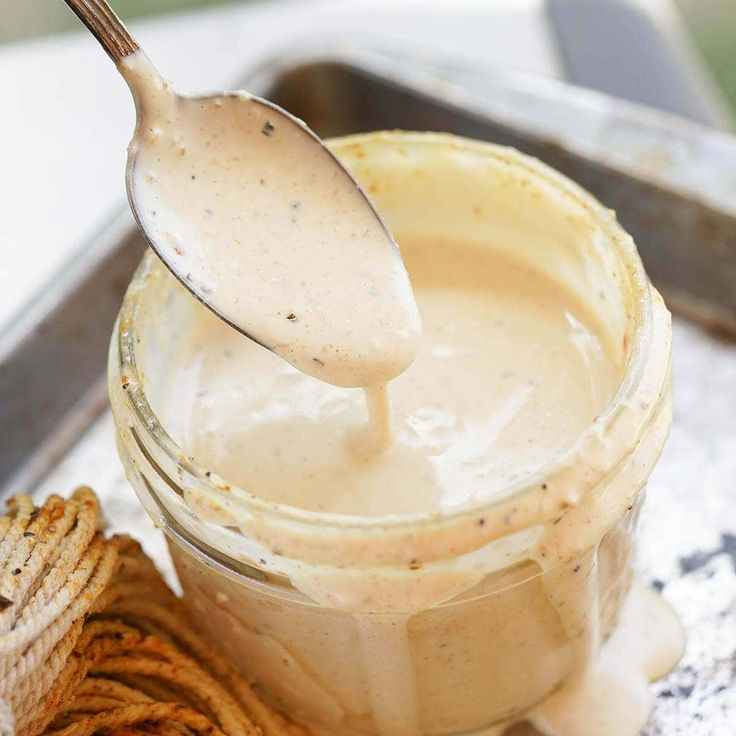 a spoon is sticking out of a jar filled with cream cheese sauce next to some pretzels