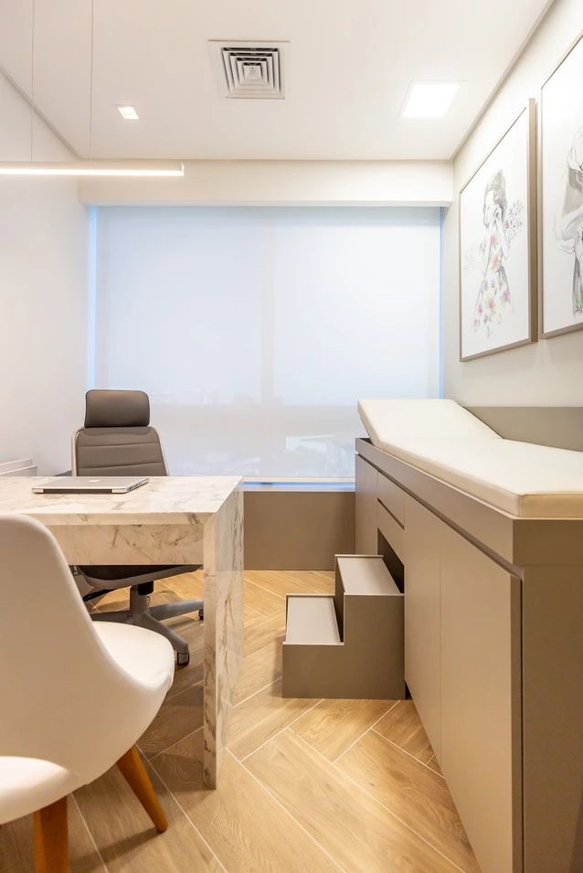 an office with white walls and wooden flooring is pictured in this image, there are two chairs at the desk