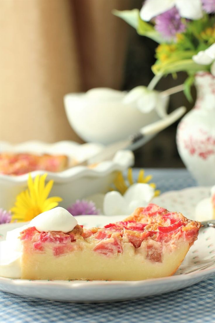 a piece of cake sitting on top of a white plate next to a vase filled with flowers