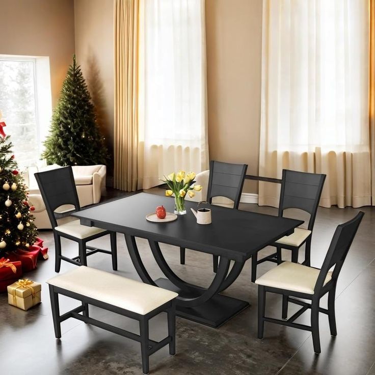 a dining room table with chairs and a christmas tree in front of the window,