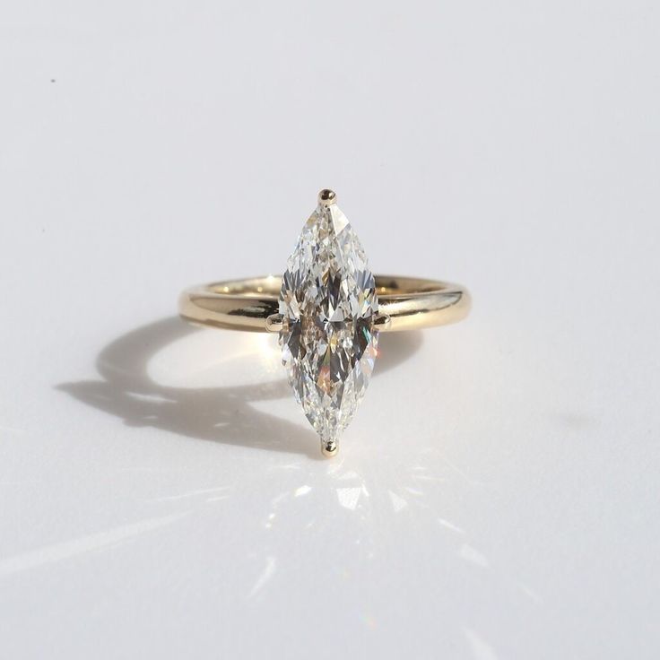 an engagement ring with a pear shaped diamond in the center, on a white background