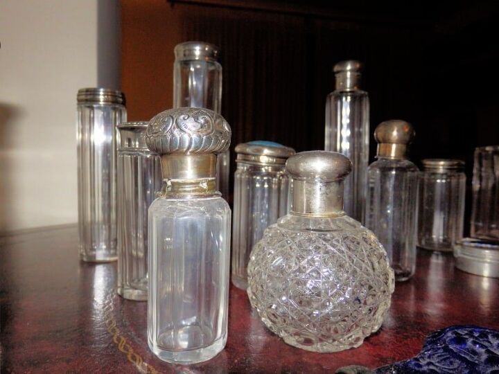 an assortment of glass bottles on a table with other items in the backround