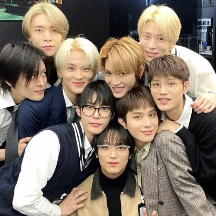 a group of young men standing next to each other in front of a tv screen