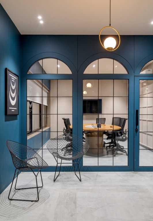 an empty conference room with blue walls and glass doors that lead into the meeting room