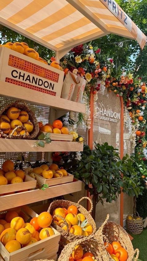 an outdoor market with oranges and other fruit in baskets on the ground under a canopy