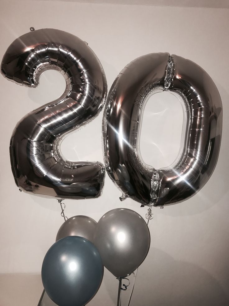 the number twenty two balloons are hanging on the wall next to some silver and blue balloons